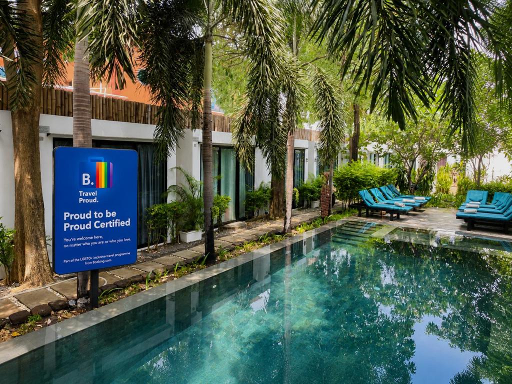 a sign in front of a swimming pool with palm trees at Tunnel Urban Retreat in Siem Reap