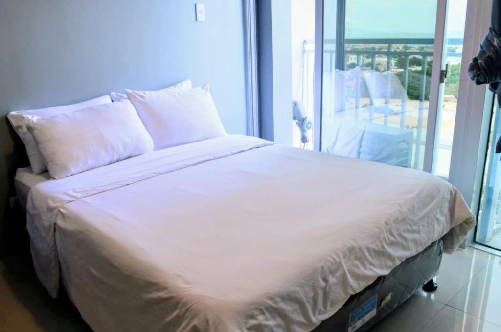 a bed with white sheets and pillows next to a window at Condo Inspiria Beside Abreeza Mall in Davao City