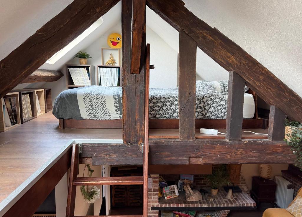 a attic room with a bed and a staircase at Le perchoir de St-Antoine - Centre historique d'Honfleur avec vue sur le port, jeux, prime, vinyles in Honfleur
