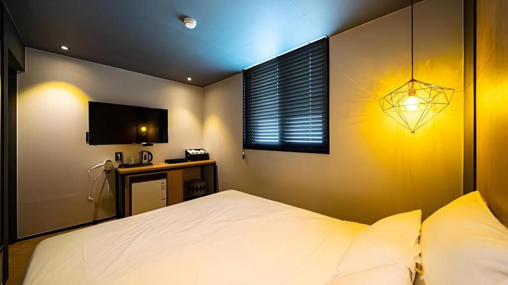 a bedroom with a white bed and a television at Hotel Deluxe in Tumo