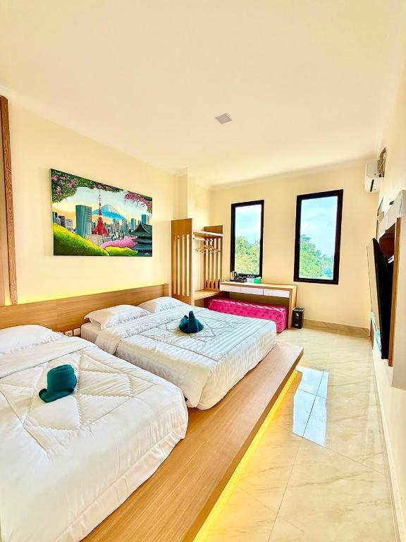 two beds in a large room with windows at Hotel Asia Express near Farmhouse Lembang in Lembang