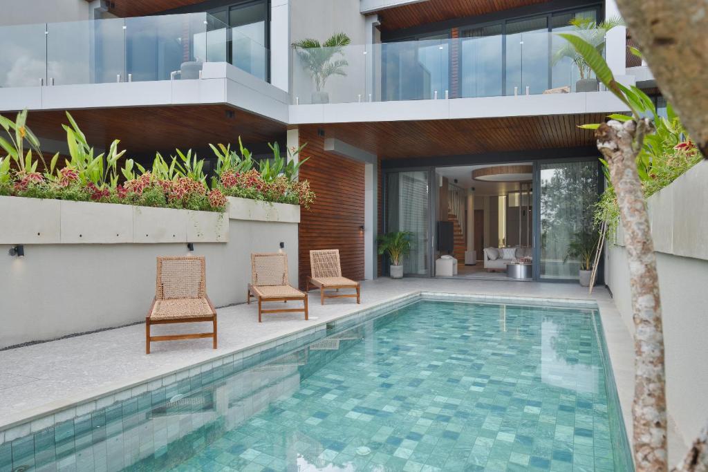 a villa with a swimming pool and two chairs at Balangan Residence in Payangan