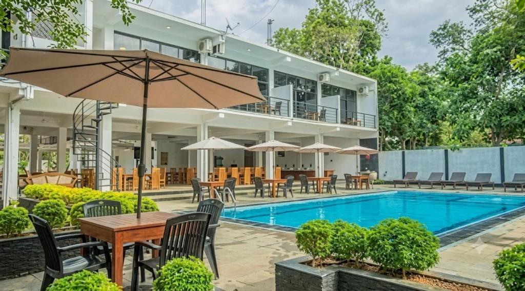 an outdoor patio with a table and chairs and a pool at Lavish Resort Sigiriya in Inamaluwa