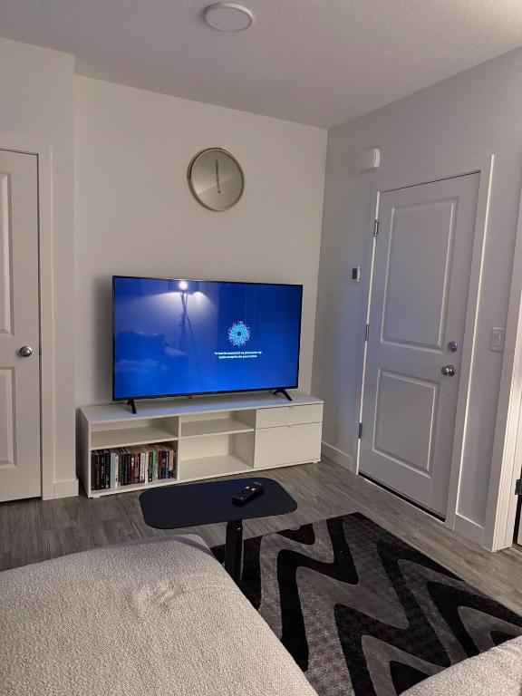 a living room with a flat screen tv on a cabinet at A very cozy 2-bedroom apartment in Calgary
