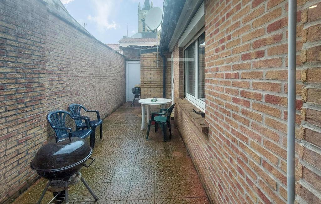 an alley with chairs and a table and a brick wall at Jolie Maison Avec Cour in Grand-Fort-Philippe