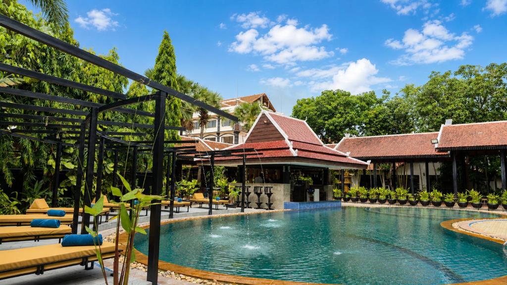 a pool at a resort with chairs and a building at The Heritage Courtyard in Siem Reap