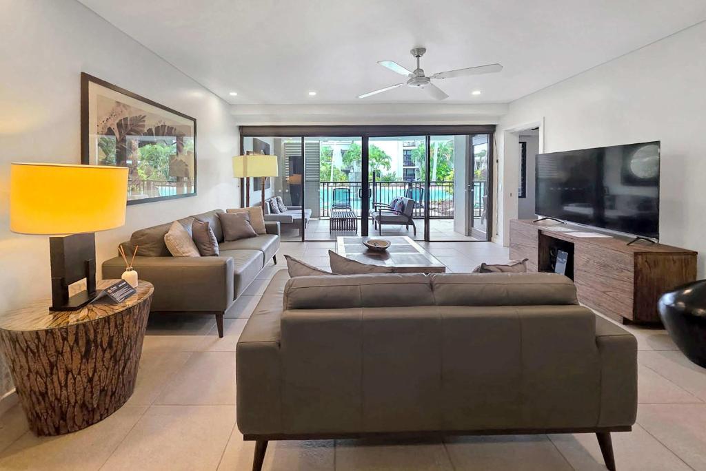 a living room with two couches and a tv at Poolside Bliss: A Modern Resort Sanctuary in Port Douglas