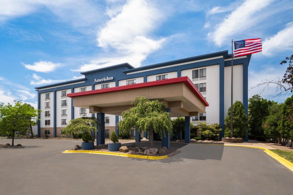 a hotel with an american flag in front of it at AmericInn by Wyndham Madison West in Madison
