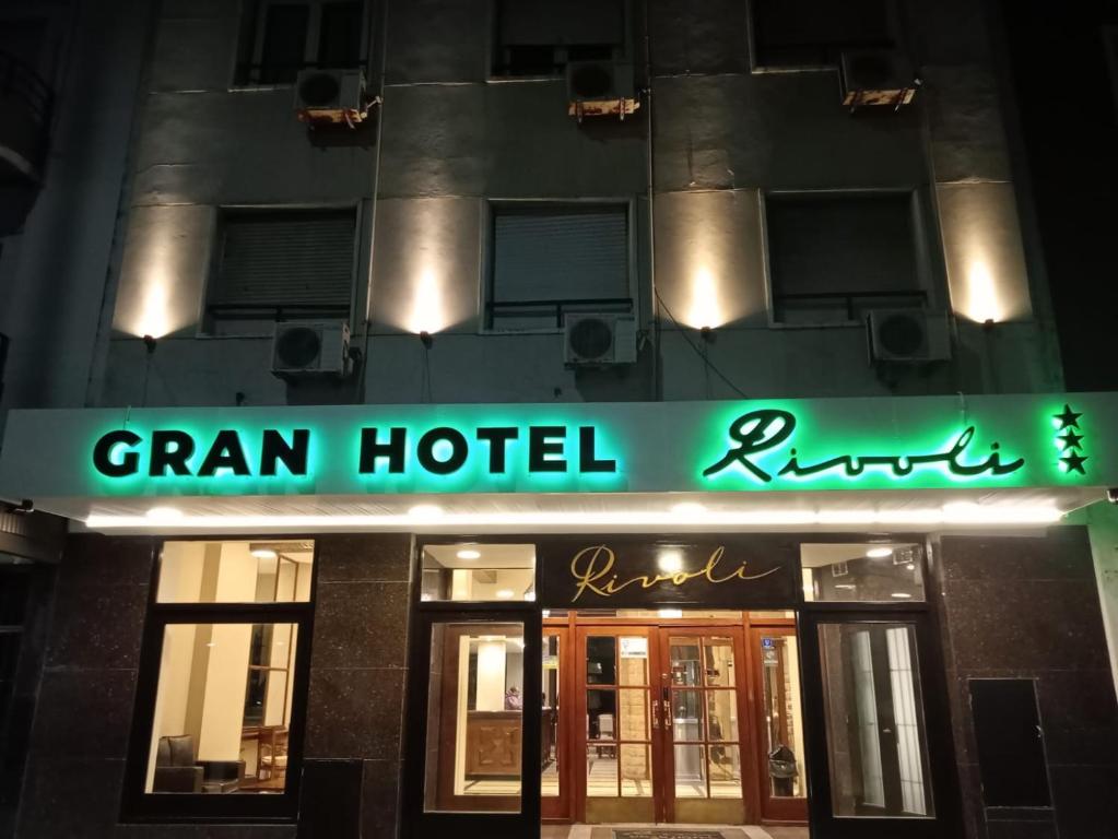 a building with a green neon sign in front of it at Hotel Rivoli in Mar del Plata