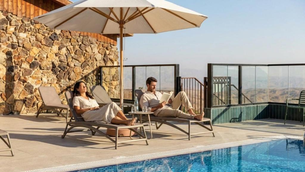 a man and woman sitting in chairs next to a pool at Roxon Desert Arad in Arad