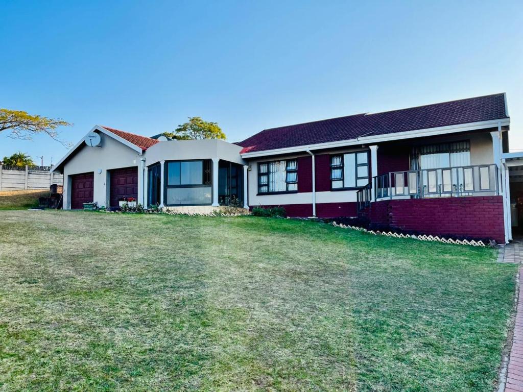 a red and white house with a yard at Emangwaneni Guest House in Kloof