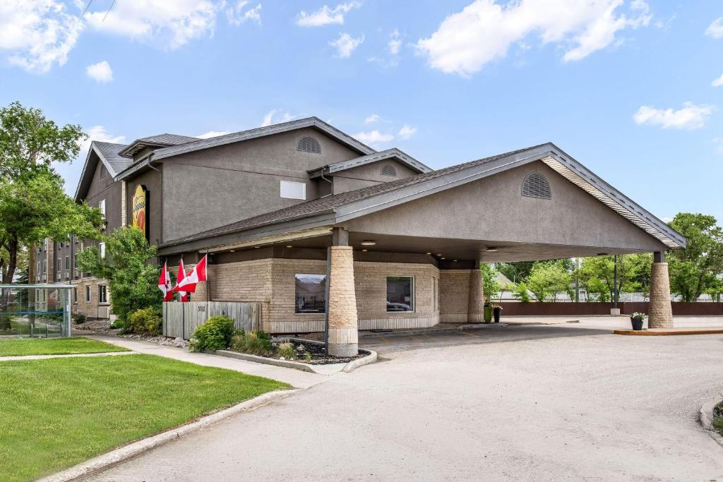 a house with a flag in a driveway at Super 8 by Wyndham Winnipeg West in Saint James