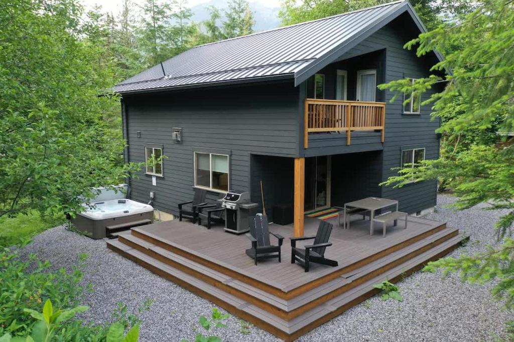 a black house with a deck with a hot tub at Wandering Rivers Retreat in Glacier