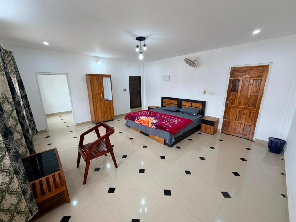 a bedroom with a bed and a chair in it at ABS Residency, Wayanad- Sulthan Bathery in Sultan Bathery