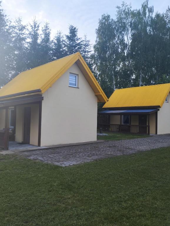 a large white building with a yellow roof at Domki pod brzózkami in Bodzentyn