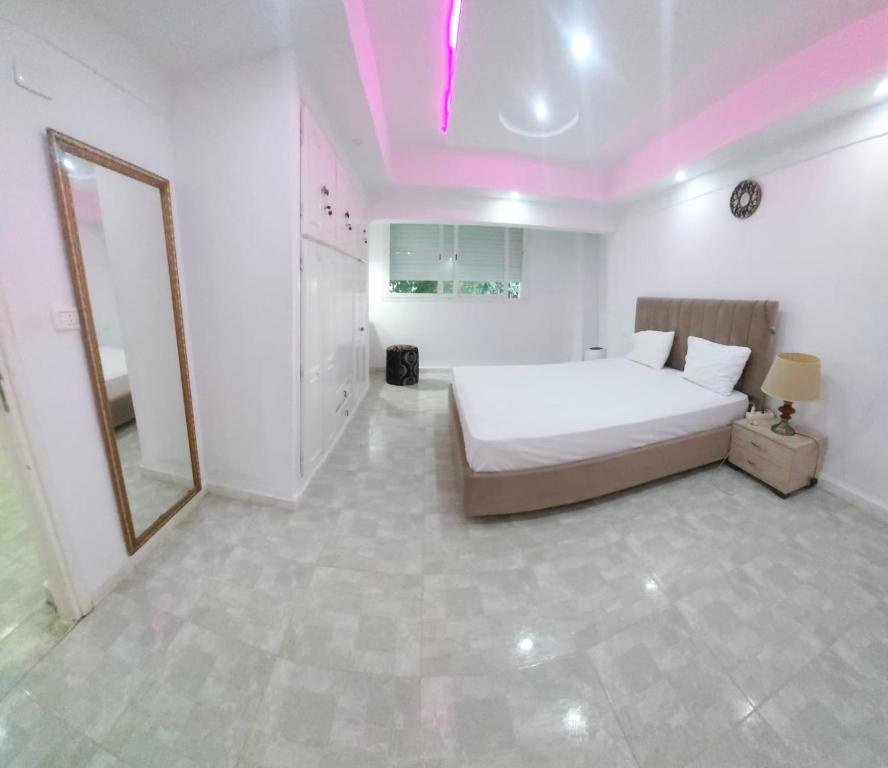 a white bedroom with a bed and a mirror at Hammamet sunrise in Hammamet