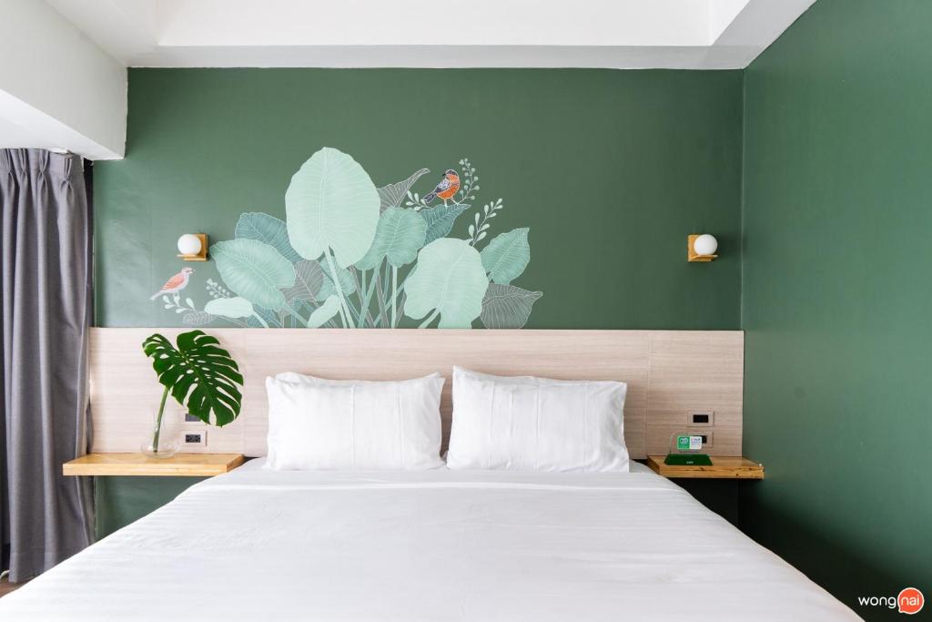 a bedroom with a white bed with a green wall at Bangkok Sleep Nest in Sathani Ban Hua Mak