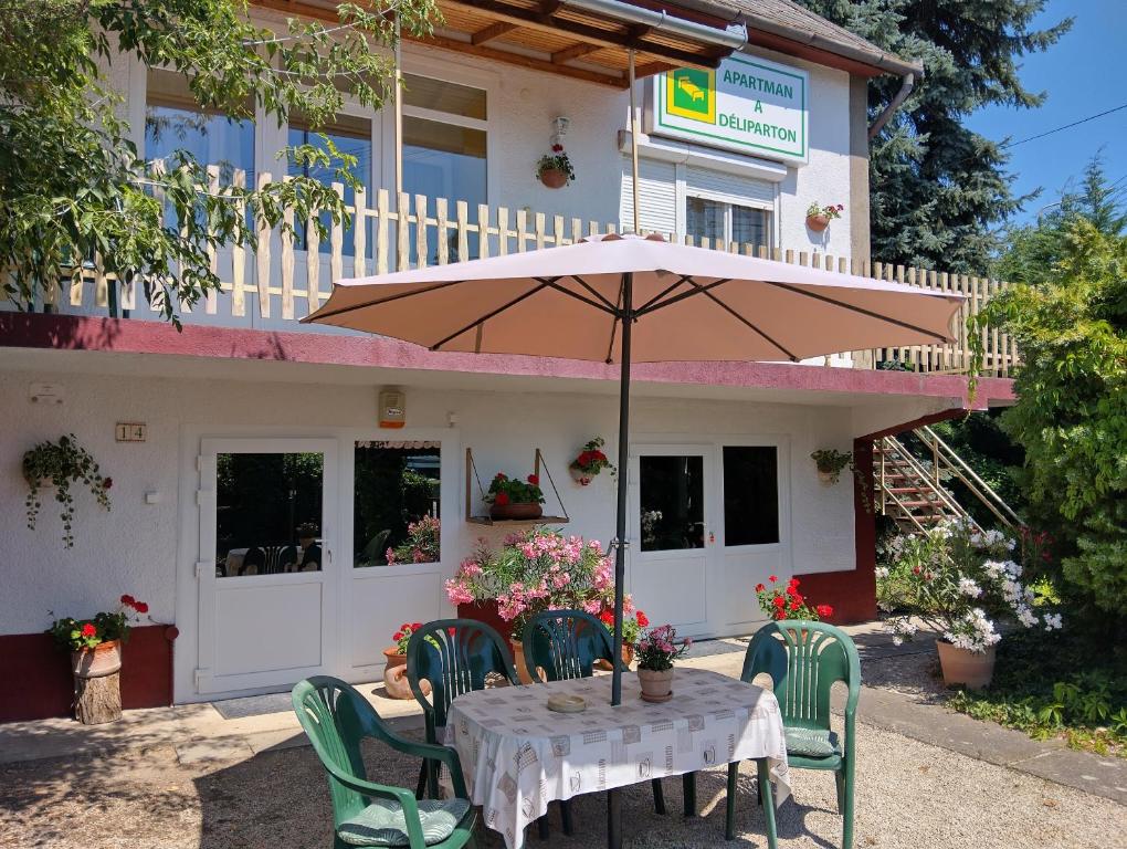 a table with an umbrella in front of a building at Apartman a Déliparton in Szántód