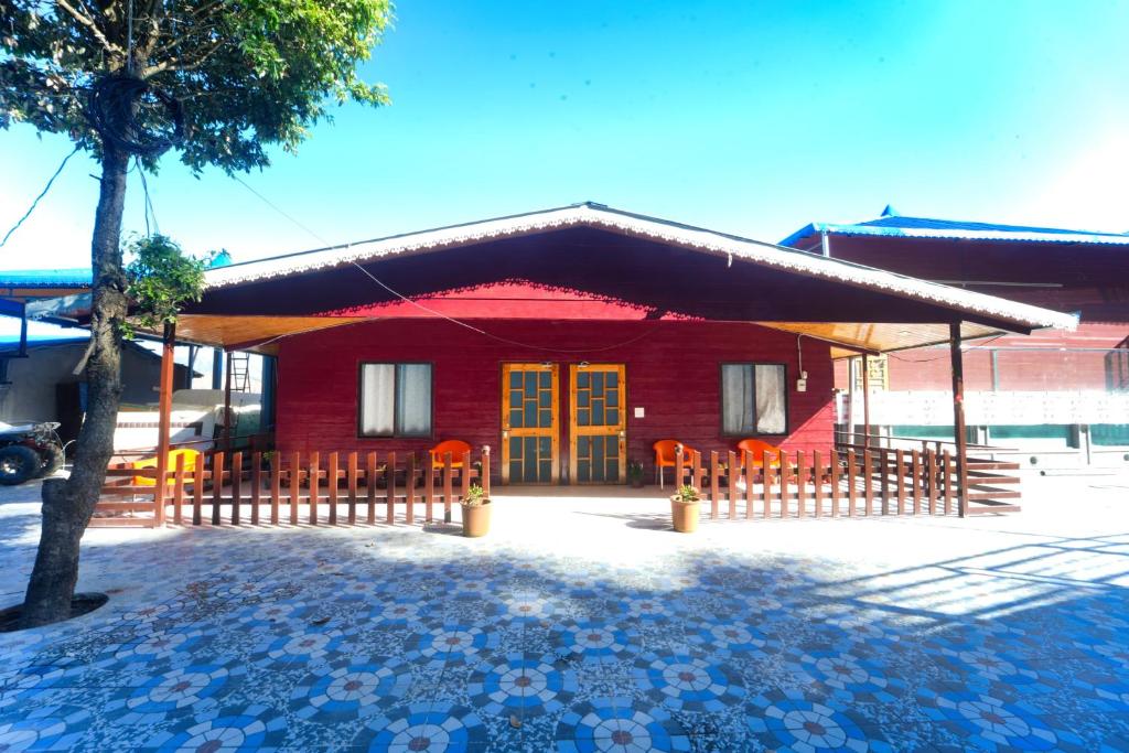 a red house with a fence in front of it at devdaar hills homes cafe & resort in Mussoorie