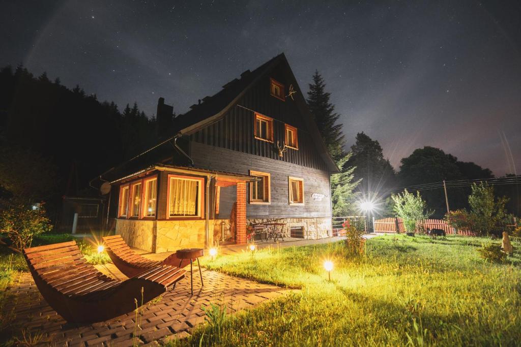a house with two chairs in the yard at night at Leśniczówka w Dolinie in Świeradów-Zdrój
