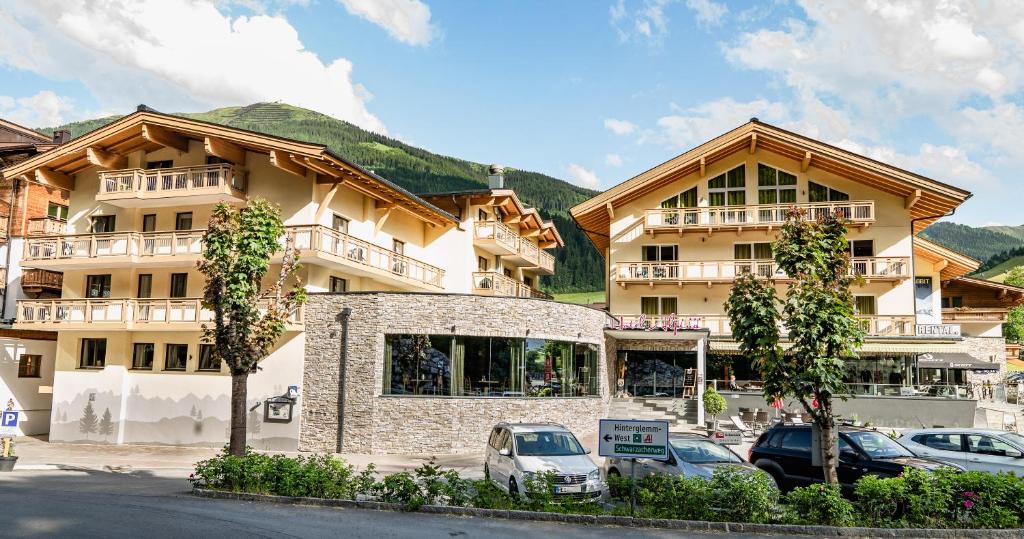 a large building with cars parked in front of it at Hotel ALPINA in Saalbach-Hinterglemm