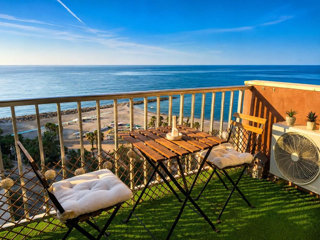 a table and chairs on a balcony with the ocean at Atico estudio en 1°linea Almuñecar in Almuñécar