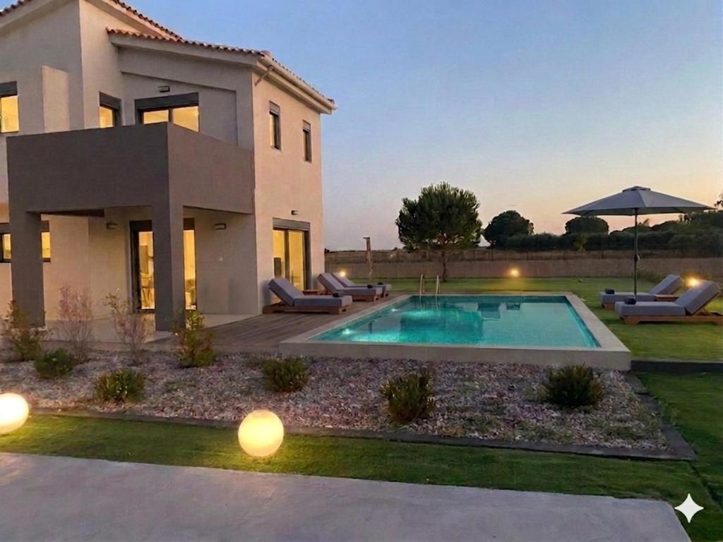a villa with a swimming pool in front of a house at Forestbreeze in Metóchion
