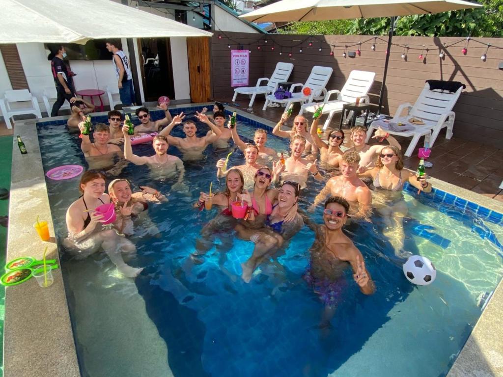a group of people are posing in a swimming pool at K-Bunk Hostel Pai Walking Street in Pai