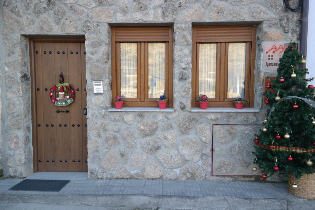 un edificio de piedra con dos puertas y un árbol de Navidad en Apartamentos Valle&Snow, en Vallejera de Riofrío