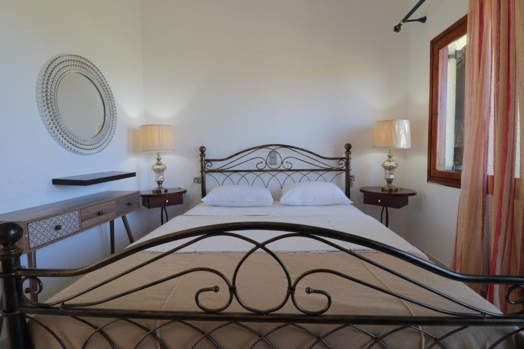 a bedroom with a bed with two lamps and a mirror at Dimitra Apartments in Sitia