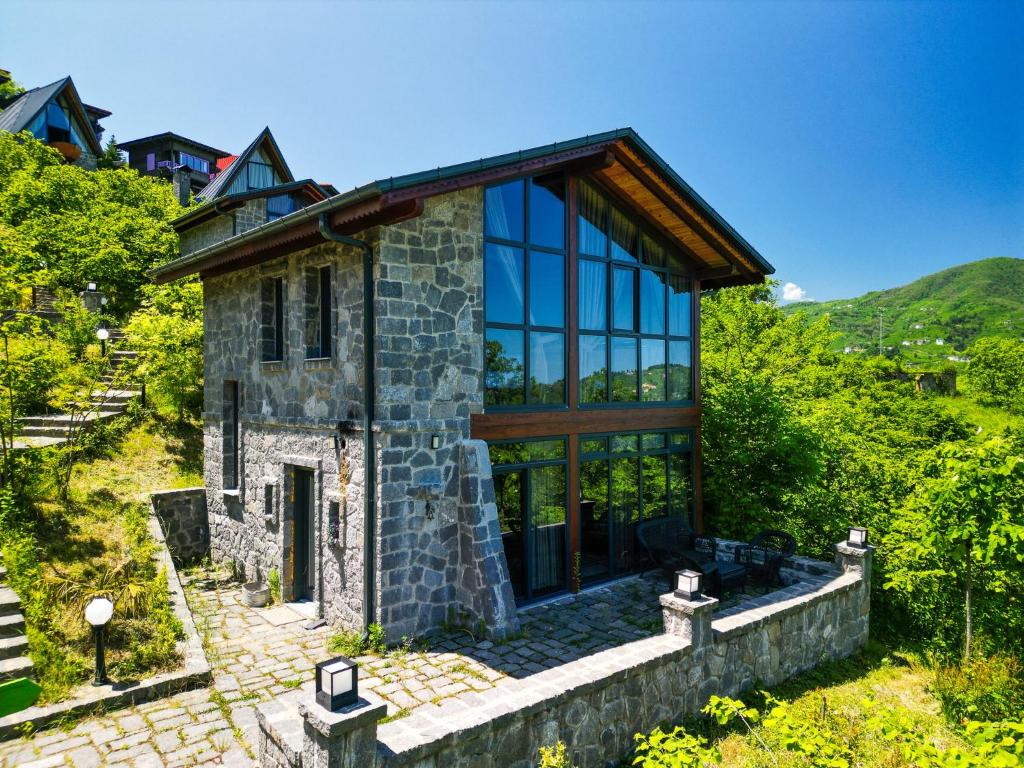 a stone house with large windows on a hill at Gafulluk Tatil Köyü in Araklı