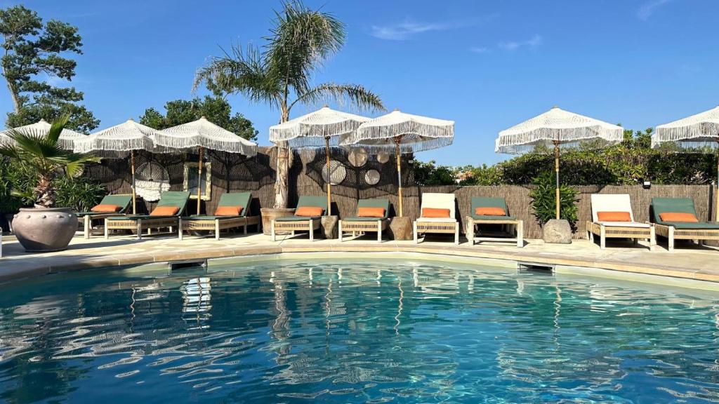 a swimming pool with chairs and umbrellas at CAPAO Beach Hôtel in Cap d'Agde