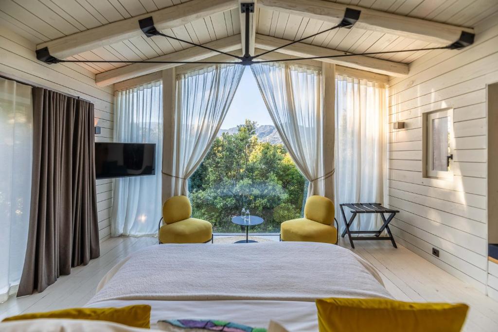 a bedroom with a large bed and two yellow chairs at Hôtel Casanghjulina in Porto-Vecchio