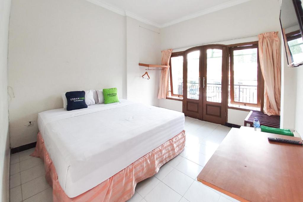 a bedroom with a large bed in a room with a window at Urbanview Hotel Grand Palem near Alun Alun Batu in Songgoriti