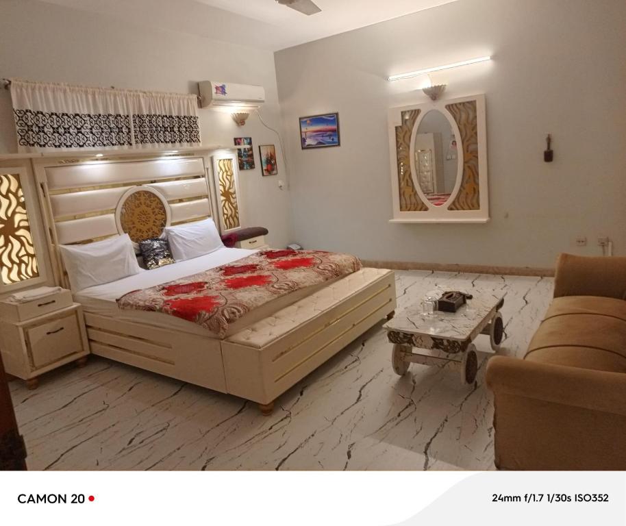 a bedroom with a bed and a couch and a mirror at Hotel Royal Inn in Karachi