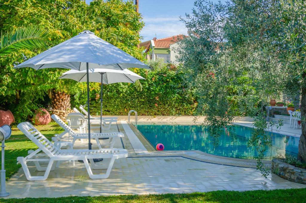 two chairs and an umbrella next to a swimming pool at Villa Eden in Limenas