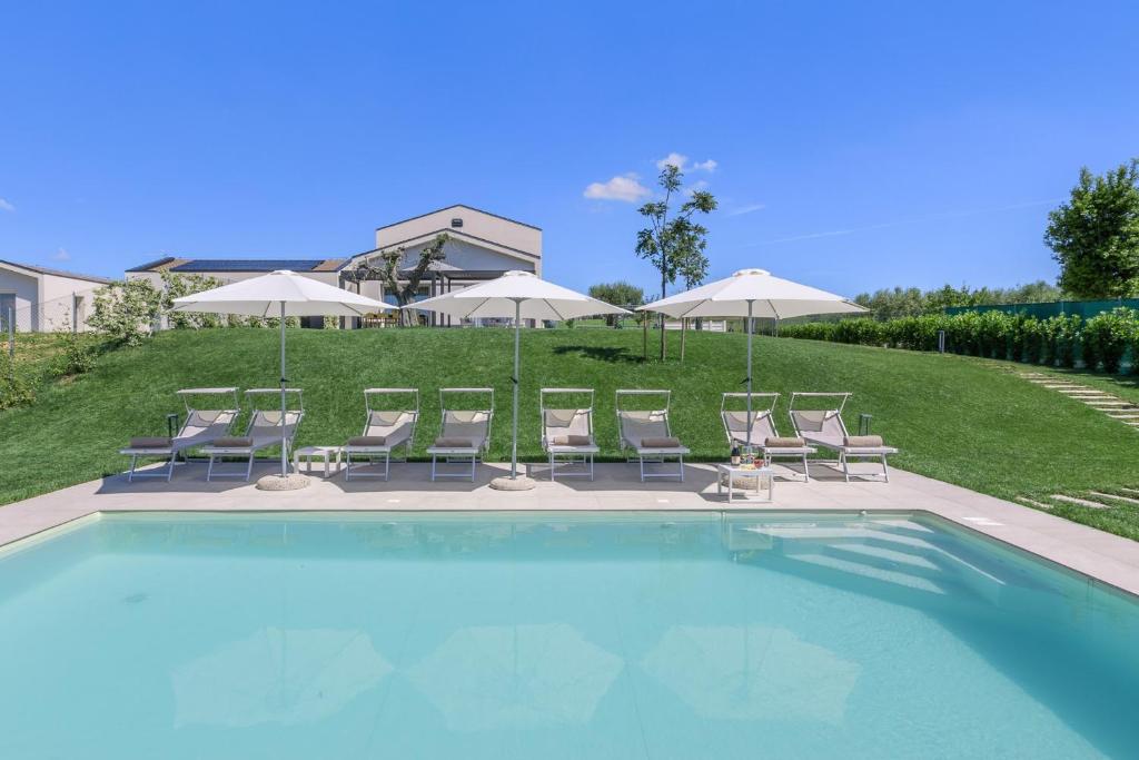 a swimming pool with chairs and umbrellas at Villa Alice in Montecosaro
