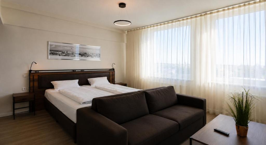 a bedroom with a bed and a couch and a window at Motel Plus Schönefeld in Schönefeld