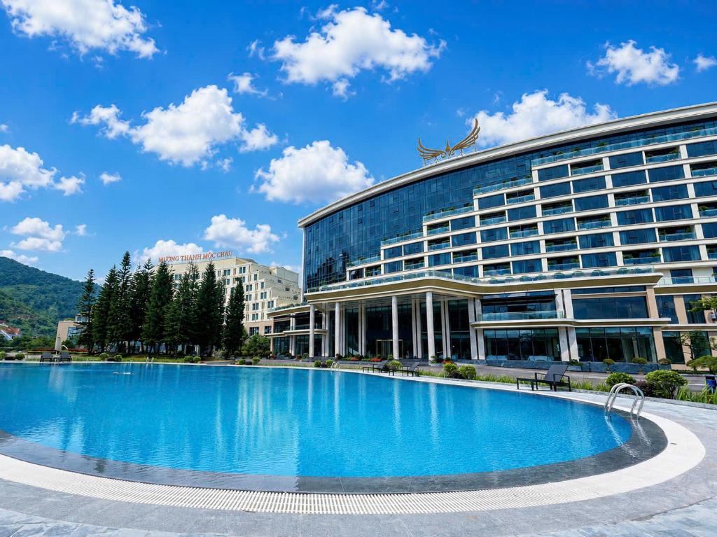 a large building with a large pool in front of it at Muong Thanh Luxury Moc Chau Hotel in Mộc Châu