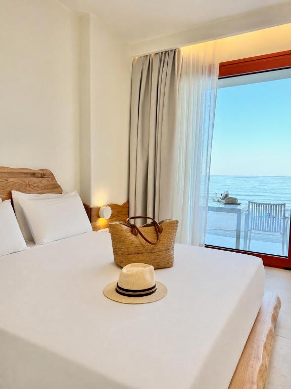 a hat sitting on a bed in a room with a window at Xanthos Beachfront Suites in Potamiá