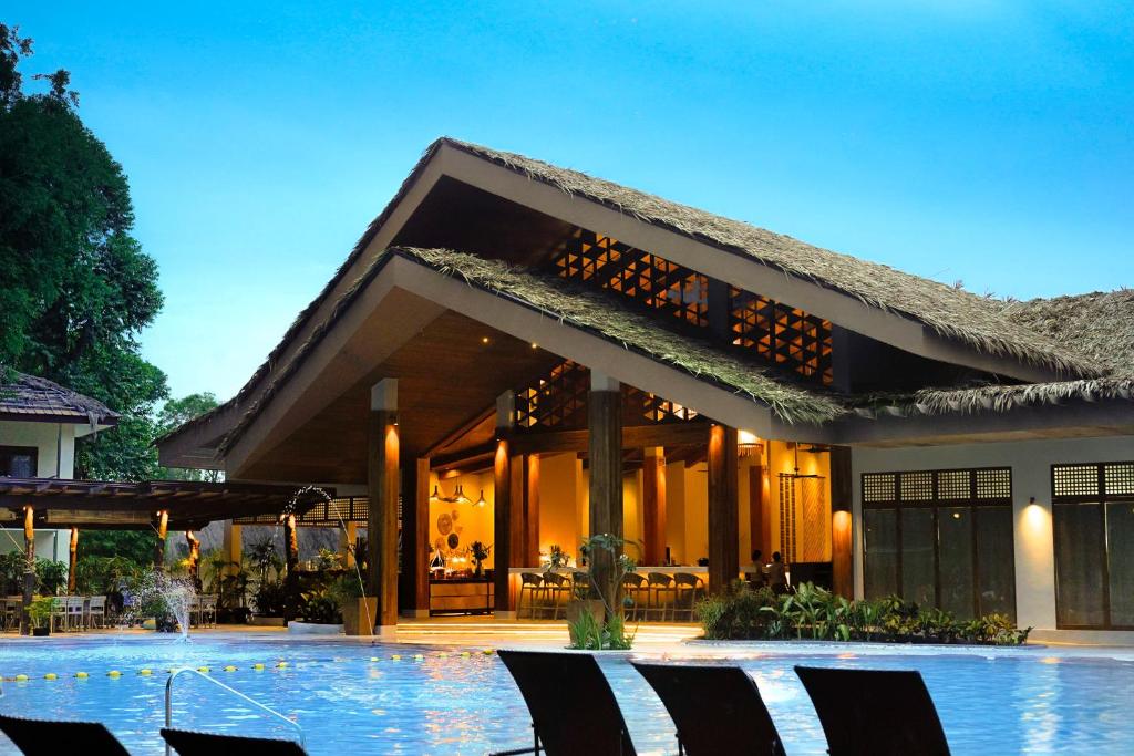 a house with a swimming pool and chairs in front of it at Bluewater Maribago Beach Resort in Mactan