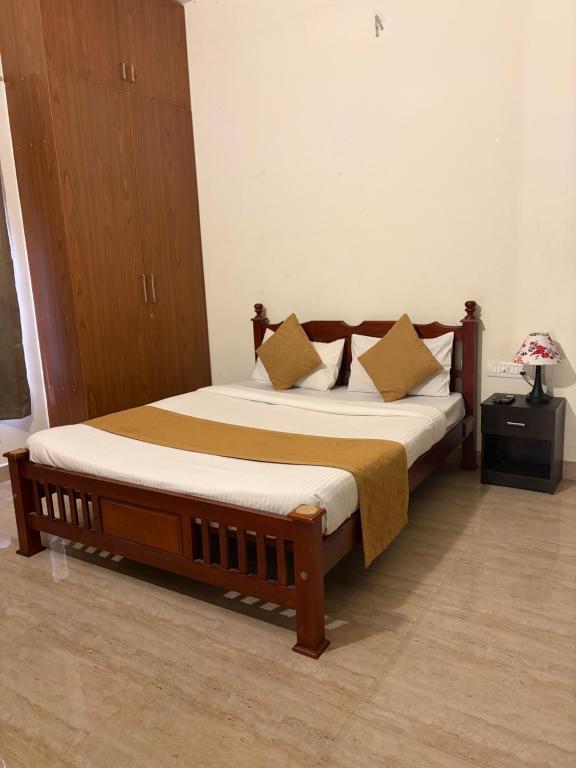 a bedroom with a wooden bed with pillows on it at Villa Ecotiva Mahabalipuram in Chennai