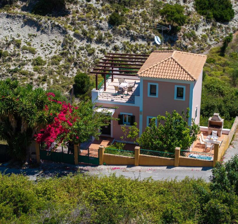 a house with a fence in front of a mountain at Villa Verde with Outdoor Jacuzzi in Divarata
