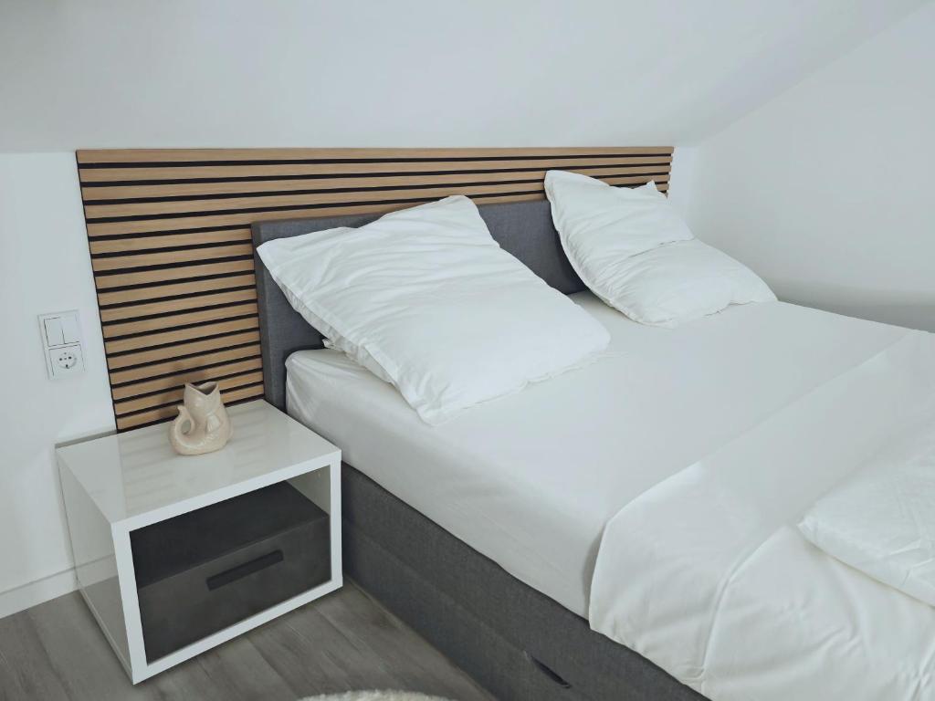 a bed with white pillows and a night stand next to it at Unterkunft in Eggenfelden in Eggenfelden