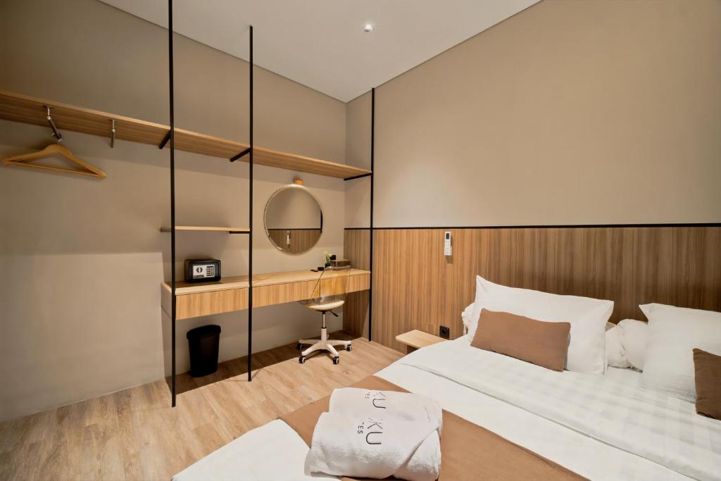a bedroom with a bed and a desk with a mirror at Oku Suites Bandung in Bandung