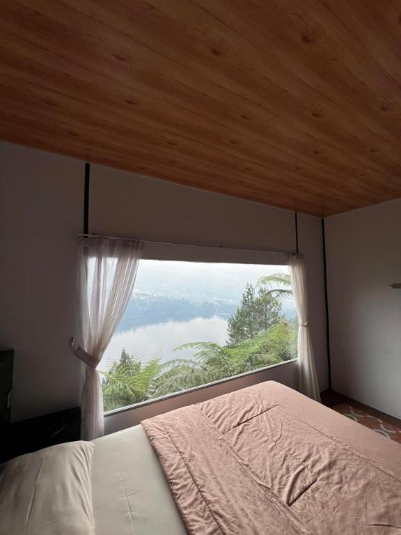 a bed in a room with a large window at Numaya Glamping Type BOX in Garung