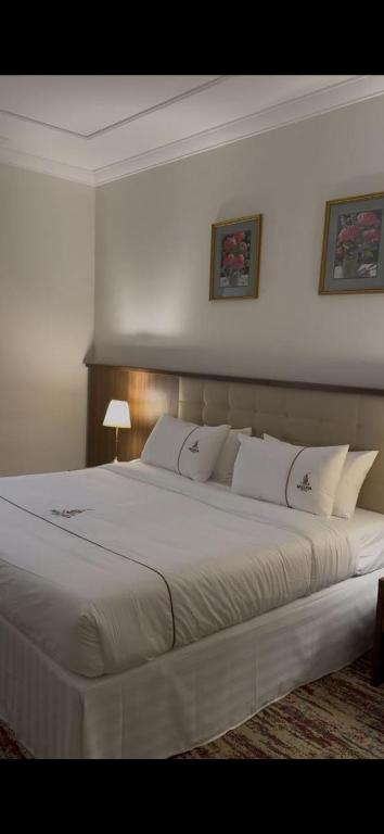 a bedroom with a large white bed with pillows at فندق مزايا in Az Zāhir