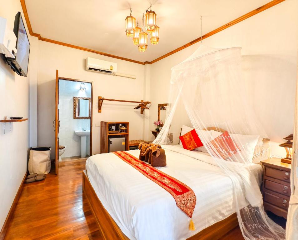 a bedroom with a large white bed and a bathroom at Aphilapa Residence in Chiang Mai