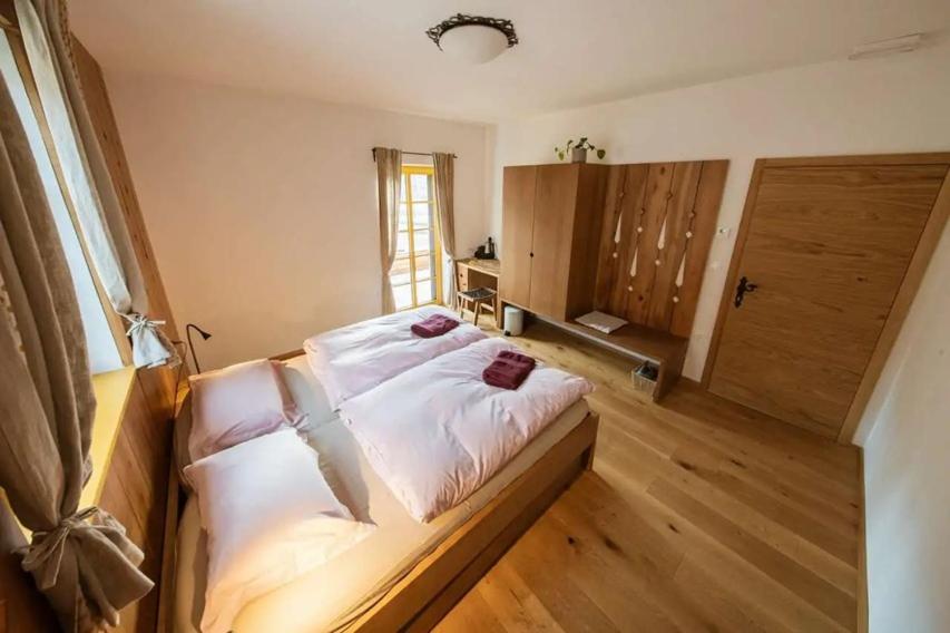 a bedroom with a bed with white sheets and a window at Hiša Tam Čez in Slovenj Gradec