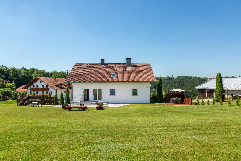 a white house with a grassy yard with benches at Die Gemütliche Fewo in Breitenberg
